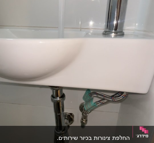 ברז וכיור עם צינורות מתחת לכיור